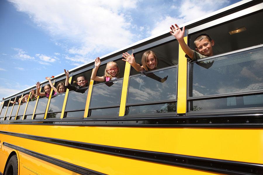 elementary school students waving from bus